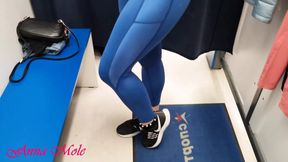 A girl with a perfect figure and small breasts, trying on various leggings in the locker room